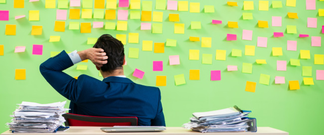 Business person looking at wall of bright post-it notes