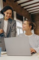 Two,Smiling,Busy,Female,Colleagues,Working,On,Project,Together,And Two smiling busy female colleagues working on project together and use laptop sitting in office